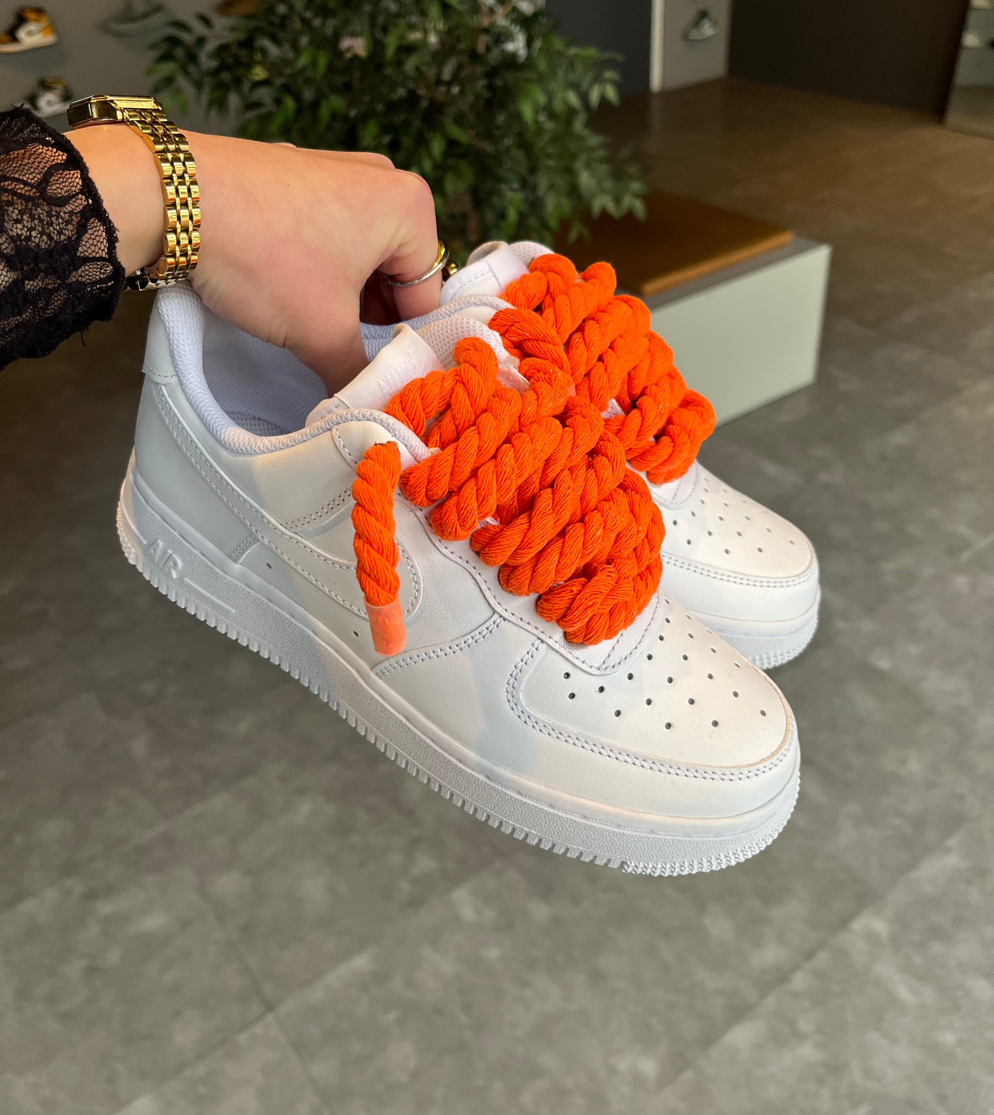 Hand houdt Nike Air Force 1 Low wit met oranje rope laces custom pair lifestyle foto outdoors