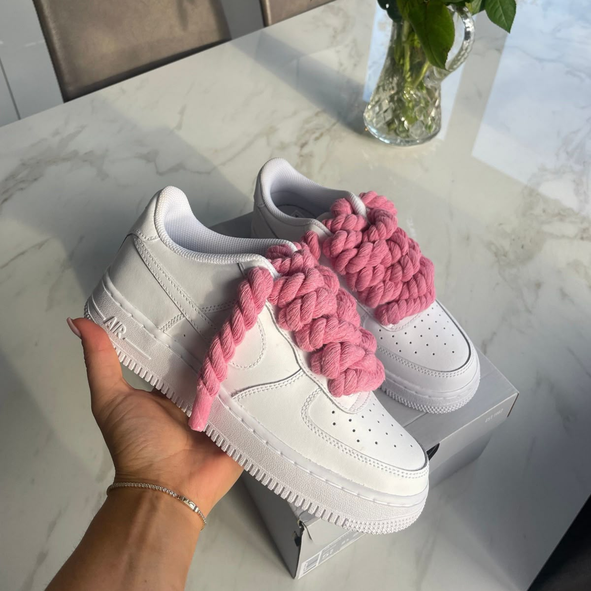 Hand houdt Nike Air Force 1 Low wit met roze rope laces custom paar