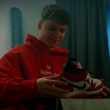 Customer inspecting red and white sneaker indoors